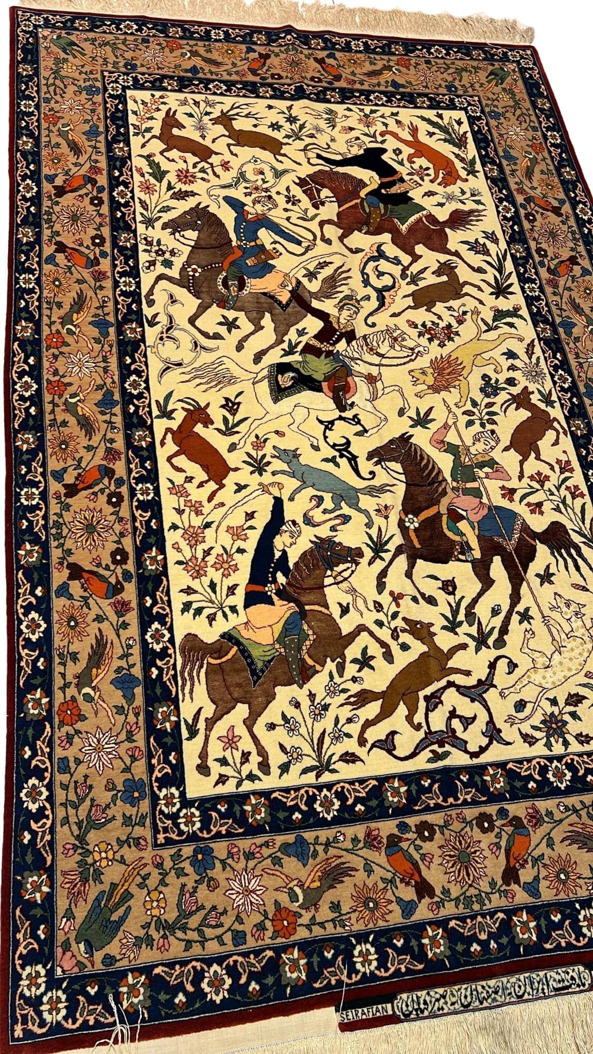 Detailed shot of a silk and wool Ahmad Seirafian rug, featuring hunting scene motifs and natural-dyed colors.